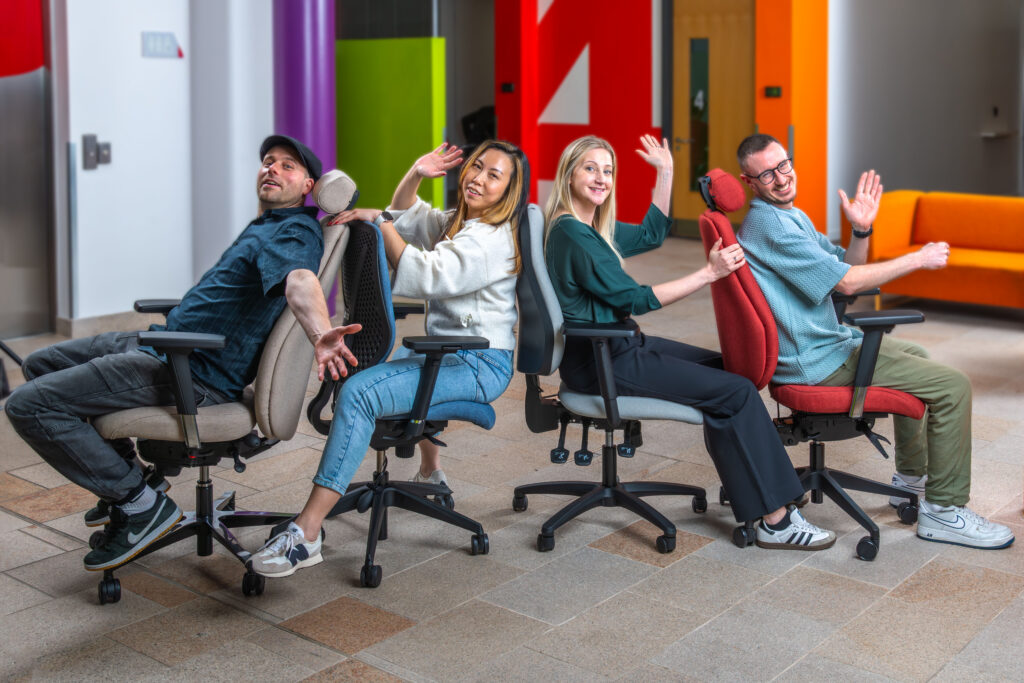 Four people sitting and posing playfully in a range of Ergochair ergonomic chairs in a colourful office space